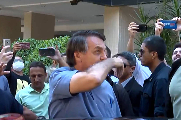 O presidente Jair Bolsonaro limpa o nariz e depois cumprimenta apoiadores em Brasília