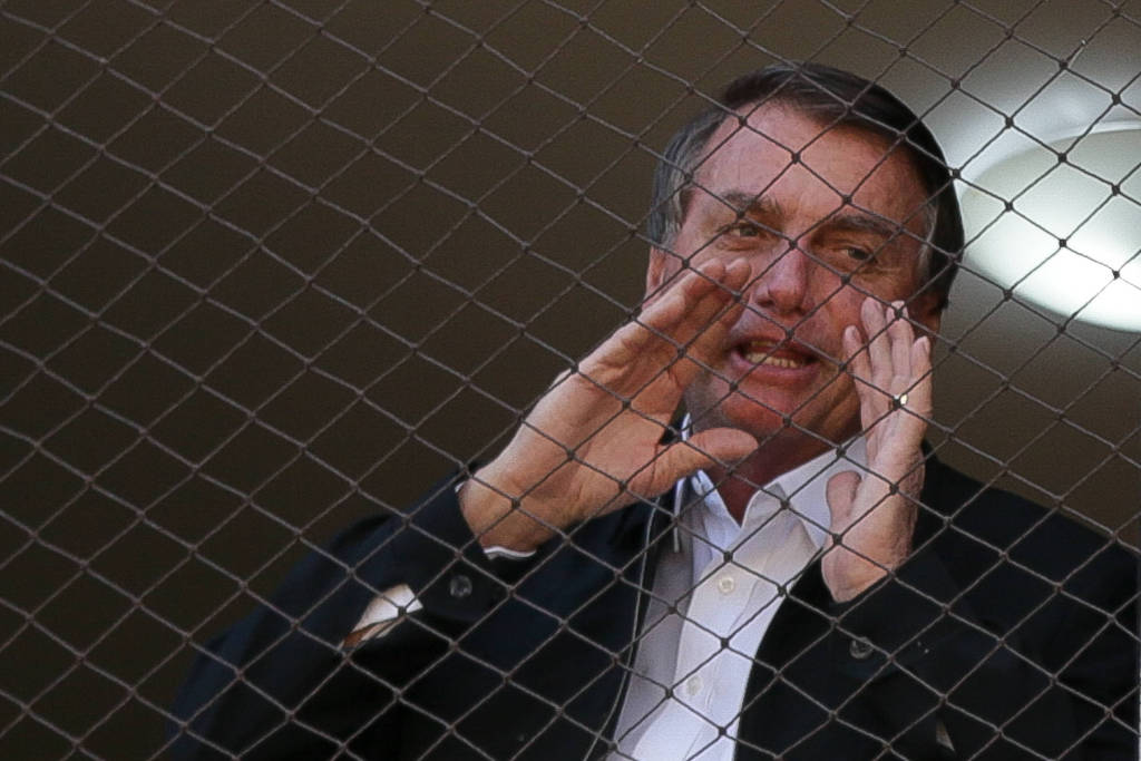 O presidente Jair Bolsonaro acena para apoiadores da janela de um prédio na asa norte, em Brasília
