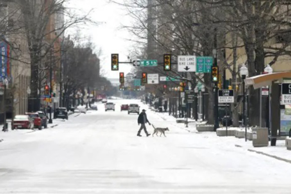 Homem caminha com cachorro por rua coberta por gelo em Forth Worth, no Texas 