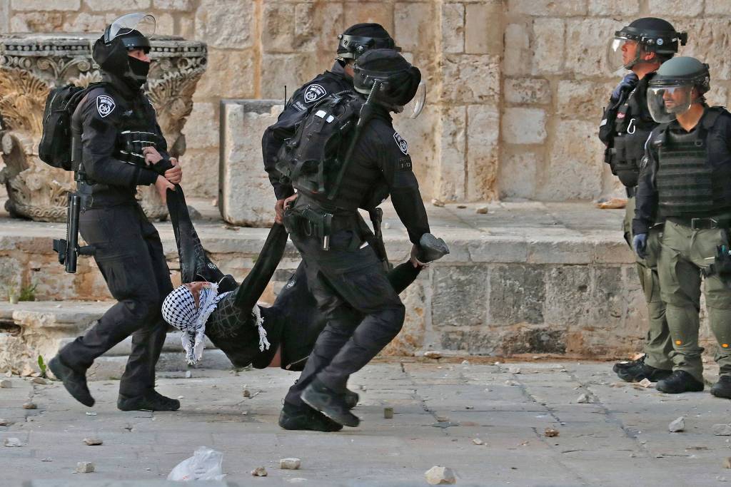 Policiais israelenses levam palestino ferido durante confronto no complexo da mesquita de Al-Aqsa, em Jerusalém Policiais israelenses levam palestino ferido durante confronto no complexo da mesquita de Al-Aqsa, em Jerusalém
