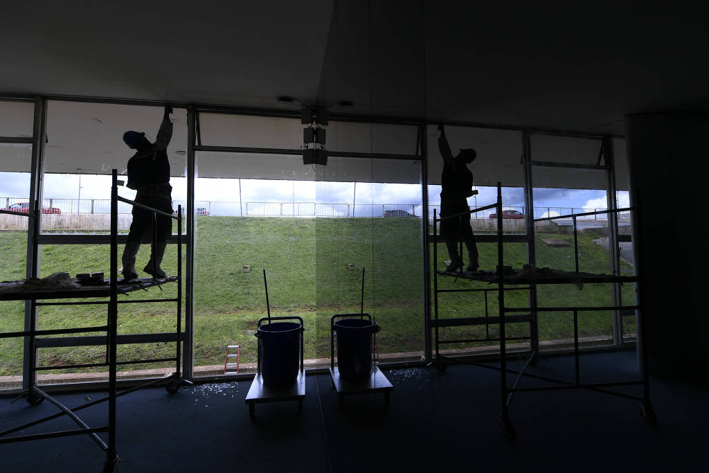 Funcionários substituem vidros quebrados na fachada do Senado Federal durante invasão ao prédio, em 8 de janeiro