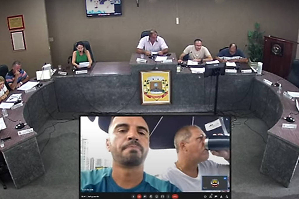 Debaixo de um guarda-sol em uma praia, vereadores participam de sessão da Câmara de Jataizinho (PR)