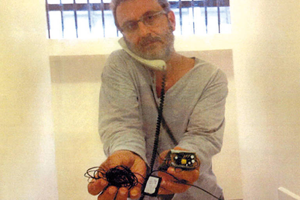 Foto de 2014 na qual o doleiro Alberto Youssef mostra equipamento que ele diz ter achado dentro da cela, na carceragem da Polícia Federal, em Curitiba