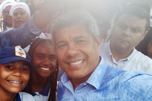 O governador Jerônimo Rodrigues posa para fotos com estudantes, com o deputado estadual Luciano Sim?es ao fundo