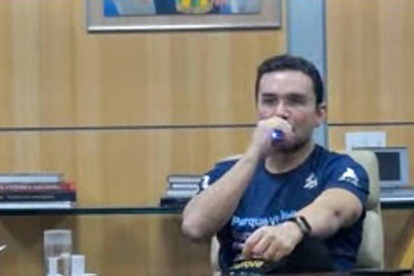 O ministro do Turismo, Celso Sabino, fuma um cigarro eletrônico em seu gabinete, em Brasília, durante transmissão nesta quinta (14) 