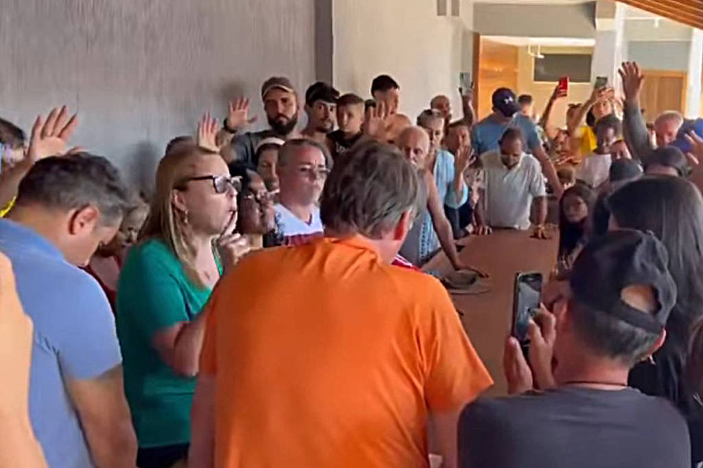 O ex-presidente Jair Bolsonaro (de laranja) participa de oração com apoiadores em sua casa de praia, em Angra dos Reis (RJ)