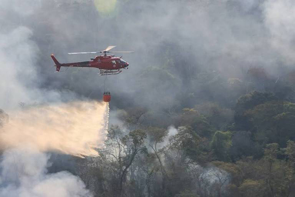 Helicóptero joga água em locais de difício acesso durante incêndio florestal no estado do Rio de Janeiro