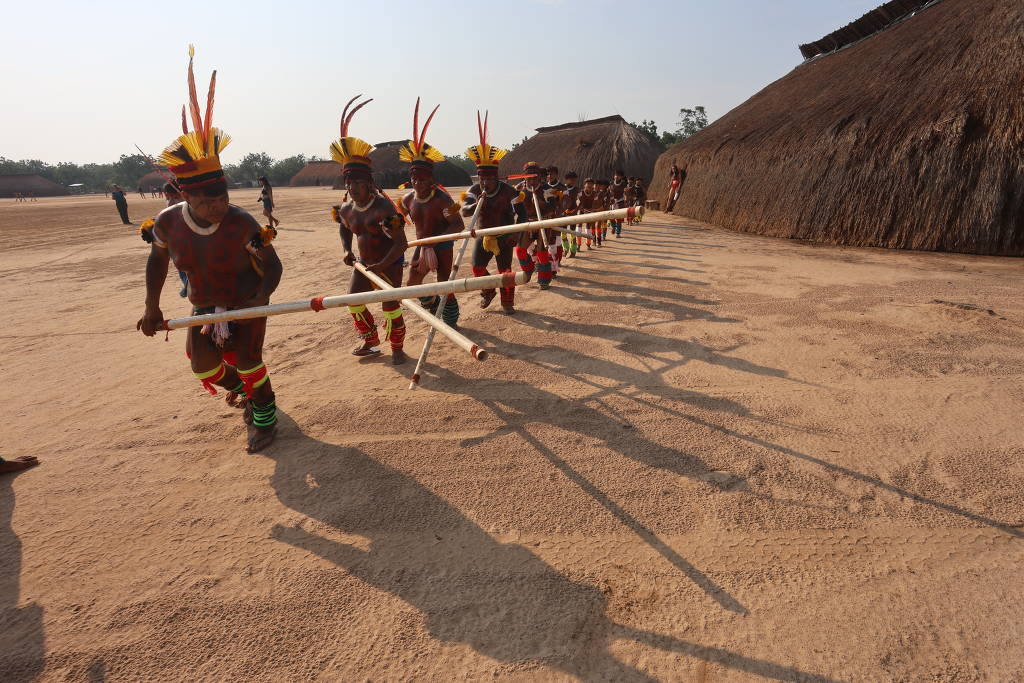 Um grupo de indígenas está se movendo em uma área de terra batida