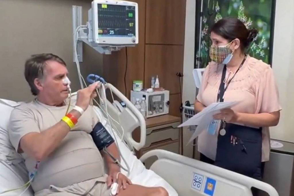 O ex-presidente Jair Bolsonaro conversa com a oficial de Justiça responsável por sua intimação em quarto de UTI, em Brasília